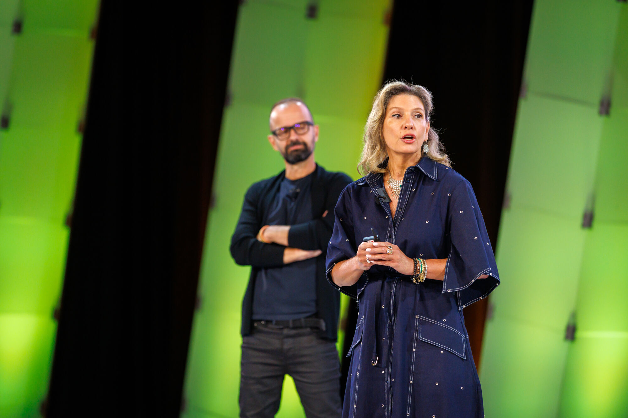 Two speakers working a point on the green-lit stage